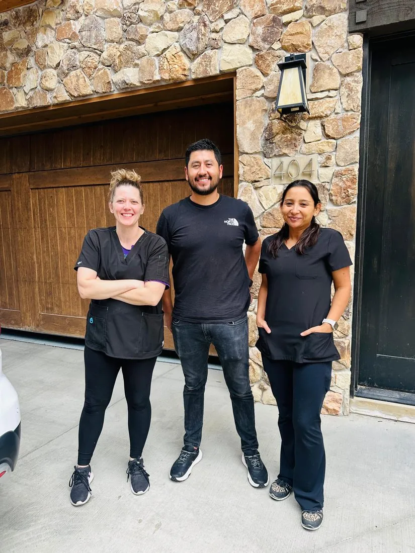Maid For You Utah cleaning team — three professional GBAC certified technicians smiling outside a client home in Utah, ready to serve