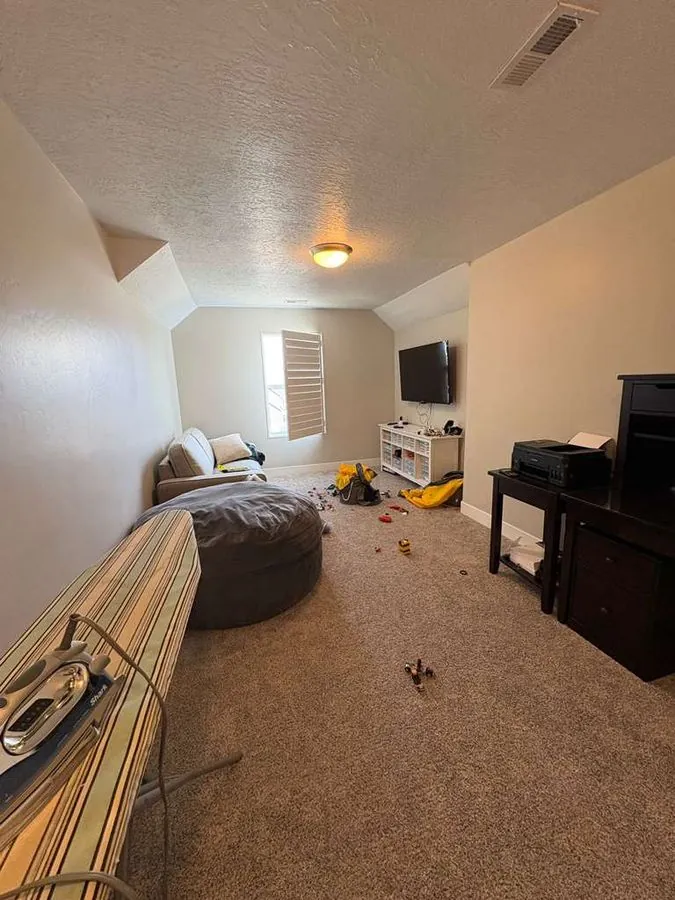 Before cleaning — cluttered lived-in bonus room with toys and items scattered across carpet in Salt Lake City Utah